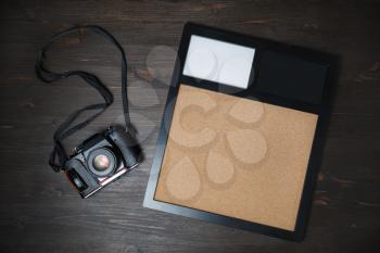 Black vintage camera and blank photo frame on wooden background. Responsive design template. Flat lay.