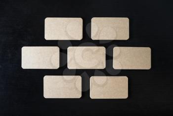 Blank kraft business cards mock-up on black wood table background. Copy space for text. Flat lay.