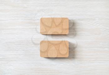 Two blank kraft business cards on light wooden background. Branding mockup. Flat lay.