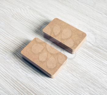 Two stacks of blank kraft paper business cards on light wooden background.