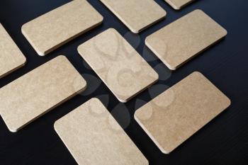 Photo of blank kraft paper business cards on black wooden background. Template for ID.