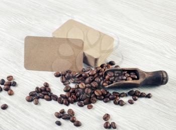 Blank kraft business cards and coffee beans on light wood table background.