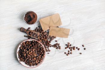 Coffee beans, blank kraft business cards and coffee ground on light wood table background. Top view. Flat lay.