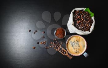 Brewing coffee background. Coffee cup, ground powder and coffee beans in canvas bag on black kitchen table background. Top view. Flat lay.