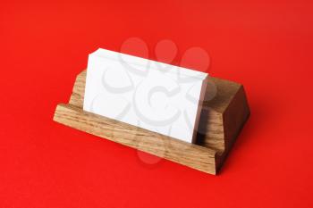 Blank business cards on wooden holder at red paper background. Responsive design mockup.
