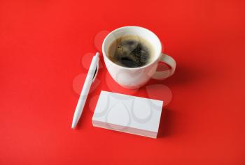 Corporate identity template. Blank business cards, coffee cup and pen on red paper background.