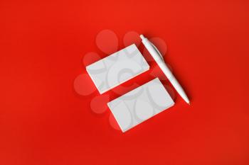 Photo of blank white business cards and pen on red paper background. Copy space for text.