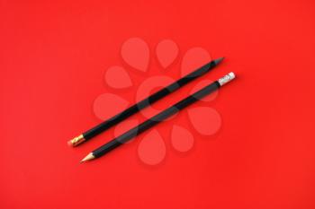 Black pencils with copy space on red paper background. Space for text.
