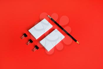 Blank business cards and pencil on red paper background. Stationery mock up. Template for placing your design.