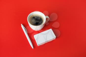 Photo of blank stationery set on red paper background. Blank business cards, coffee cup and pen. Responsive design mockup.