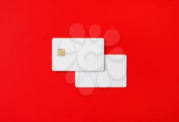 Photo of two blank credit cards on red paper background. White bank cards. Top view. Flat lay.