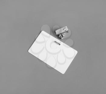 Blank badge on gray paper background. Blank plastic id card. White plastic badge.
