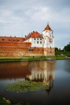 Mir, Belarus - August 04, 2017: Ancient medieval castle with towers in Mir, Belarus. Fortress and its reflection in the lake. UNESCO world heritage site. Vertical shot.
