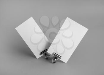 Photo of blank business cards and metal binder clips on gray background. Branding ID template.