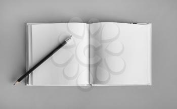Blank sketchbook and pencil mock up on gray paper background. Top view. Flat lay.
