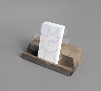 Wooden card holder with blank business cards on gray paper background.