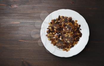 Raisins in plate on wood table background. Flat lay.