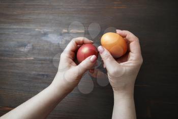 Easter eggs in female hands on wooden background.