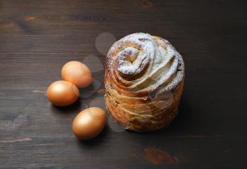 Delicious sweet bun and eggs on wooden background.