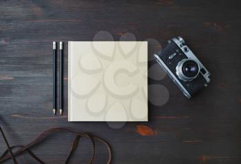 Blank stationery: book, pencils and retro camera on wood table background. Flat lay.