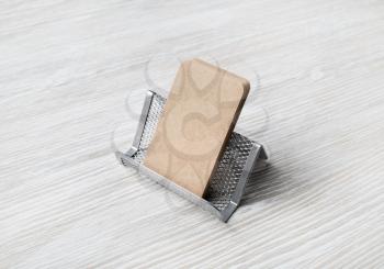 Card holder with blank kraft business cards on light wood table background.
