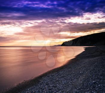 Horizontal dramatic sunset on stony beach background backdrop