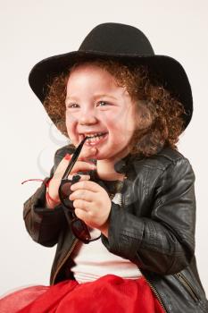 Little girl with black hat sitting and laughing