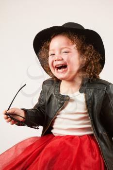 Little girl with black hat sitting and laughing