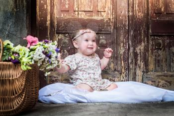 Portrait of beautiful smiling baby girl on the background of the vintage old door. Close-up