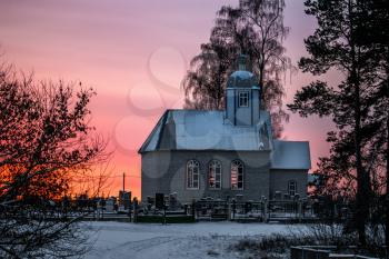 Small Christian church in the village at sunset. Winter times