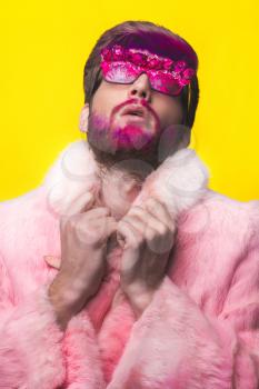 Portrait of glamour man with red beard. Guy in a pink fur coat and funny  sunglasses.