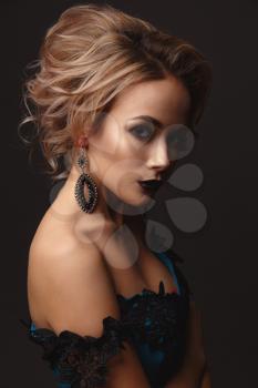 Studio Portrait of a young gentle sexy model girl with stylish makeup on a dark background