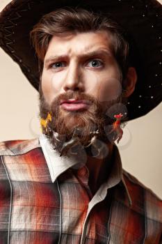 Young man in a cowboy hat and toy horses in a beard