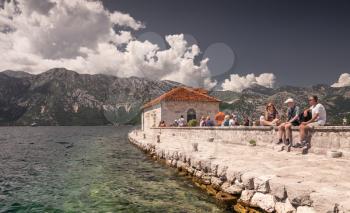 Perast, Montenegro - 07.11.2018.  Tourists on the pier of the island near the old church in the Bay of Kotor, Montenegro