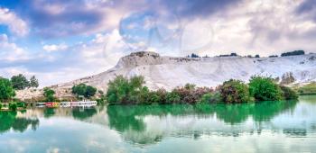 Pamukkale, Turkey – 07.15.2019. White mountain and green lake in Pamukkale. Panoramic view from the side of the village on a summer morning