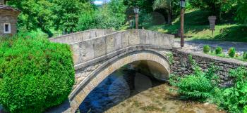 Stone bridge in the Etar Architectural Ethnographic Complex in Bulgaria on a sunny summer day. Big size panoramic photo.