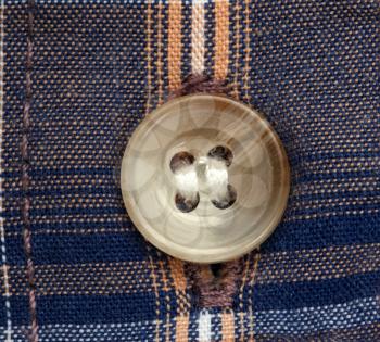 Close up view of a button over checked shirt