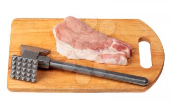 Pork stake on a wooden board with a meat hammer