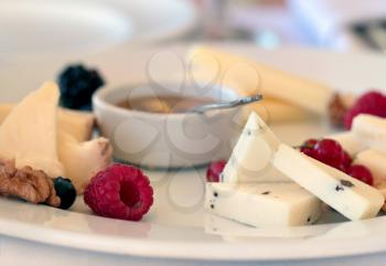 Cheese plate with honey, nuts and berries