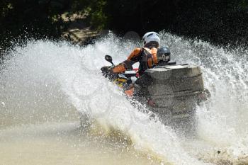 The man on the ATV crosses a stream. Tourist walks on a cross-country terrain.