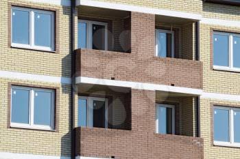 Balconies and windows of a multi-storey new house. New house of brick.