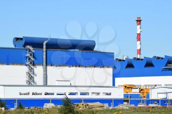 Big plant for processing scrap metal. Huge factory old metal refiner. Blue roof of the factory building. Exhaust pipes, radiators, cooling industrial units as well as office buildings.