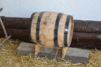 Classic wooden barrel. Barrel on stand standing on wooden bar in the barn on the floor of the straw.