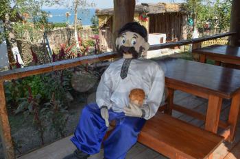 Doll Cossack sitting on a bench with a beer. Recreating historical image.