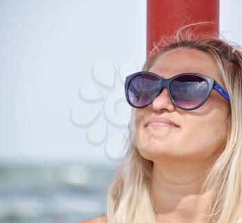 The blonde in sunglasses on the beach. Girl resting on the beach.