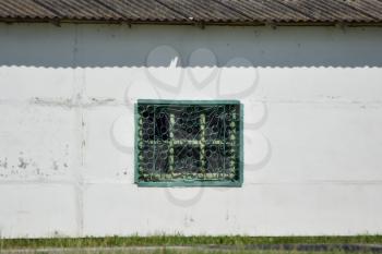 Window with green bars. The window on the white wall.
