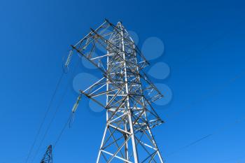 Supports high-voltage power lines against the blue sky.