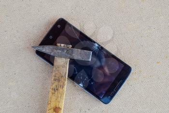 Hammer and smartphone. The screen of the smartphone, a broken hammer. The destruction of the phone.