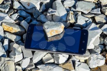 Frustrated phone on the rocks. Glass shattered on rocks on a smartphone. Smartphone fell and crashed.