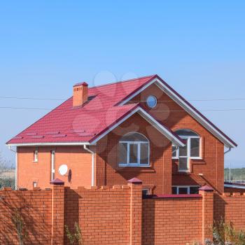 house with a red roof and red brick. Red brick fence. Roof of metal